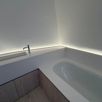 An undermounted bath in a Corian surround joined seamlessly to the washbasin worktop in a loft bathroom