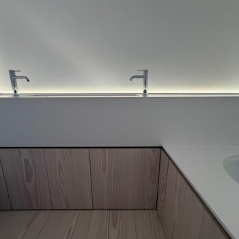 Front view of a Corian washbasin trough with a slot drain and two chrome pillar taps