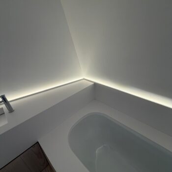 Corner of a Corian bath surround with an LED light slot running along the wall